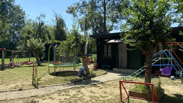Široki pogled na dvorište Denić Raja sa drvenim objektima i drvećem